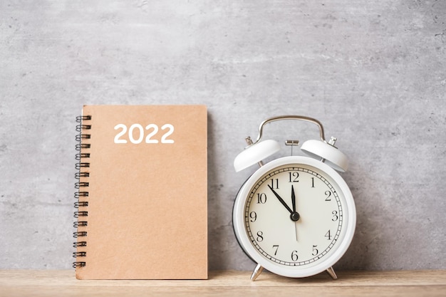 Feliz año nuevo con reloj despertador vintage y calendario 2022. Navidad, nuevo comienzo, resolución, cuenta atrás, metas, plan, acción y concepto de motivación