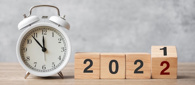 Feliz año nuevo con reloj despertador vintage y cambio de 2021 al bloque 2022. Navidad, nuevo comienzo, resolución, cuenta atrás, metas, plan, acción y concepto de motivación