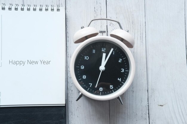 Feliz año nuevo texto en calendario con reloj en mesa