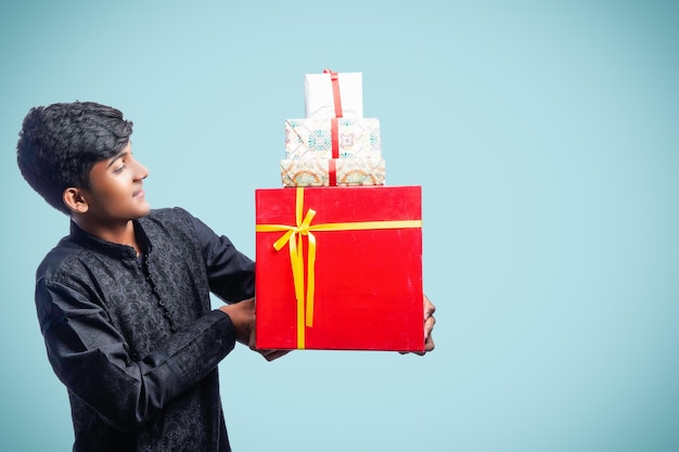 Feliz apuesto hombre indio vestido con ropa tradicional sosteniendo cajas de regalo celebrando el festival diwali aislado de fondo blanco