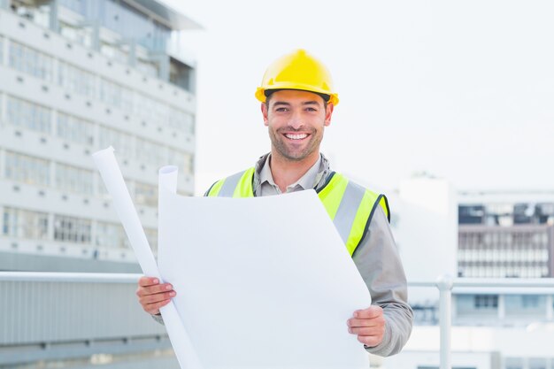 Feliz arquiteto, segurando planos fora do prédio