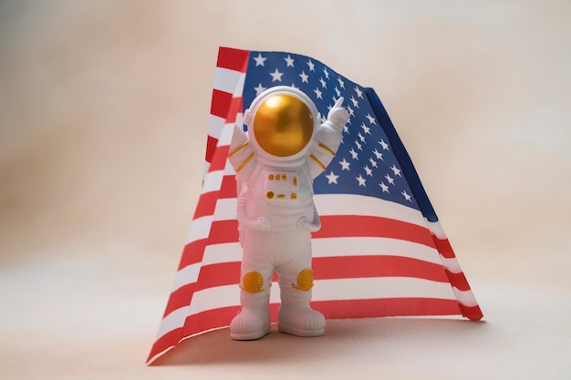 Feliz astronauta de pie con las manos levantadas sobre el fondo de la bandera de estados unidos