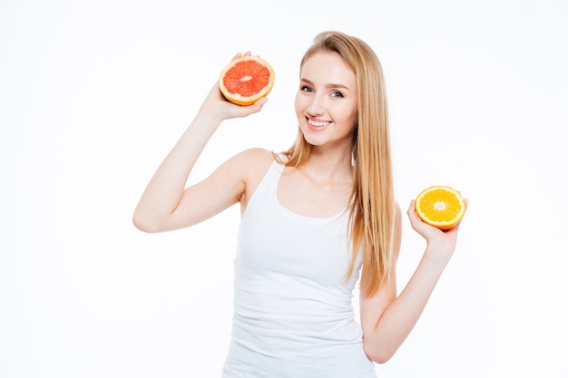 Feliz atractiva mujer sosteniendo naranja y pomelo aislado sobre un fondo blanco.