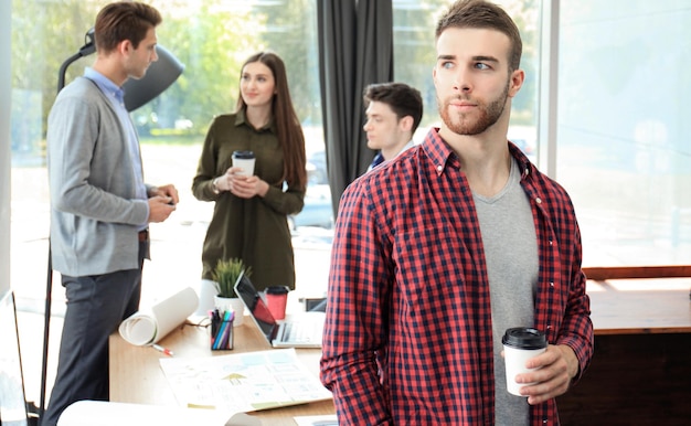 Feliz atractivo joven empresario tomando café en la oficina