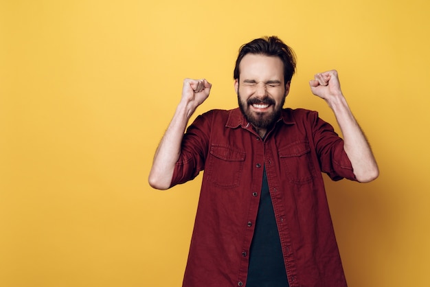 Feliz, atraente, jovem, homem barbudo, cerrando, punhos