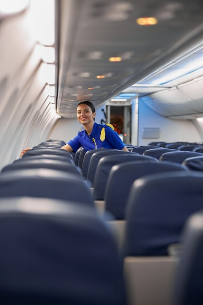 Foto feliz azafata profesional está preparando el salón antes de volar la noche