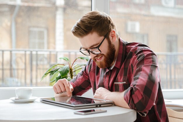 Feliz barbudo jovem usando computador tablet.