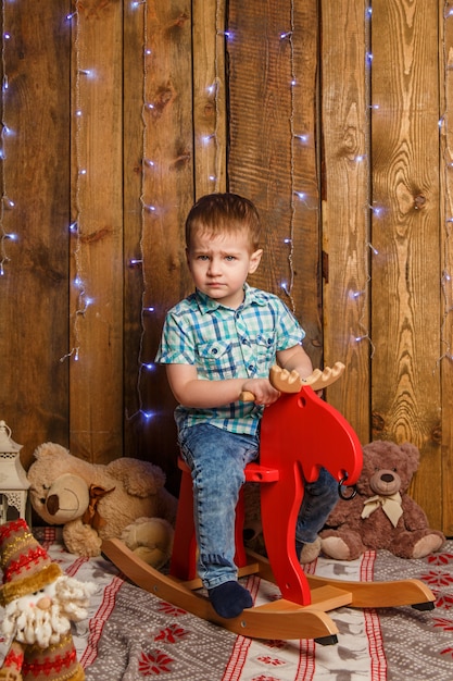 Feliz bebê menino bonitinho no cavalo de balanço