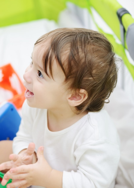 Feliz bebê sentado na cama brincando com brinquedos