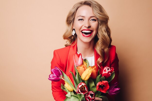 Feliz bella mujer posando con flores y riendo