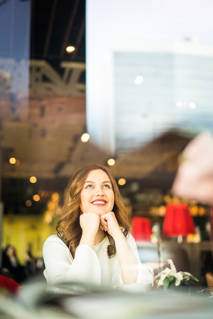 Feliz bella mujer sentada en el restaurante con doble exposición