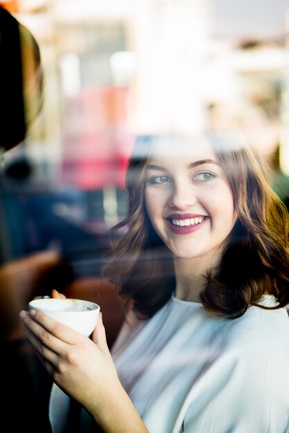 Feliz bella mujer sentada en el restaurante con doble exposición