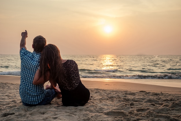 Feliz bonita pareja mirando el mar al atardecer