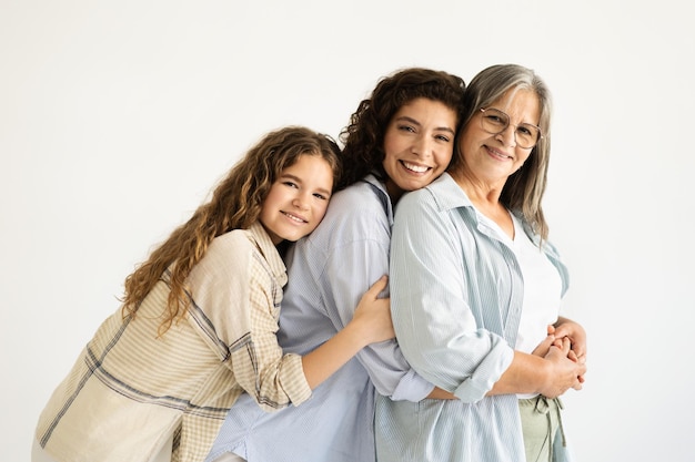 Feliz bonito adulto europeu e adolescente mulher e menina abraçando avó velha isolado em branco