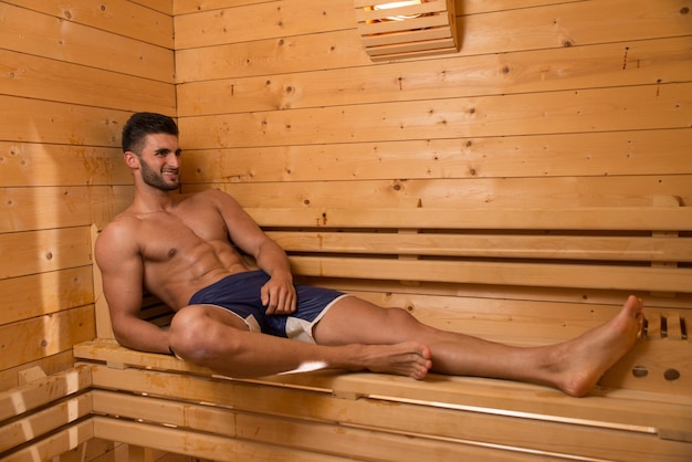 Feliz buen aspecto y atractivo joven con cuerpo musculoso relajante en sauna caliente