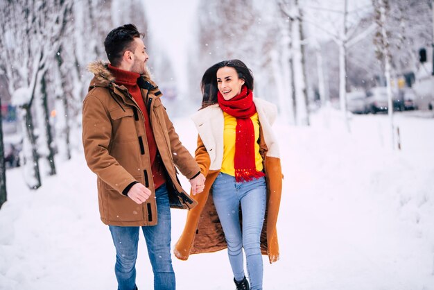 Feliz y buen día con el amado. Emocionada pareja joven enamorada caminan juntos en el parque de la ciudad de invierno y se divierten