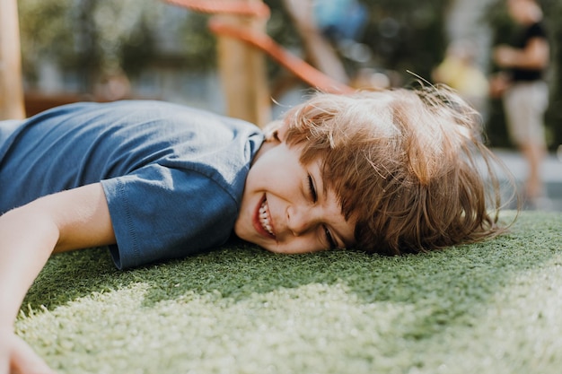 Feliz cansado depois de treinar a criança encontra-se na grama verde e descansa. menino moreno está envolvido em esportes ao ar livre. criança ativa saudável. estilo de vida. espaço para texto. Foto de alta qualidade