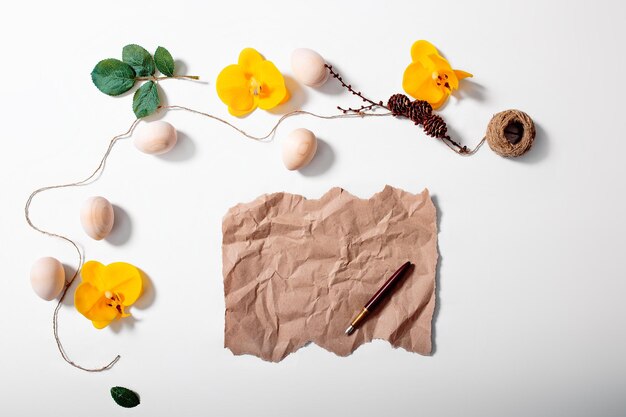 Feliz cartão de Páscoa com ovos de madeira de corda e flores de orquídea em fundo branco Papel artesanal com espaço de cópia