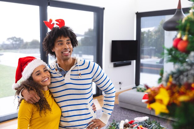 Foto feliz casal afro-americano abraçando ao lado da árvore de natal