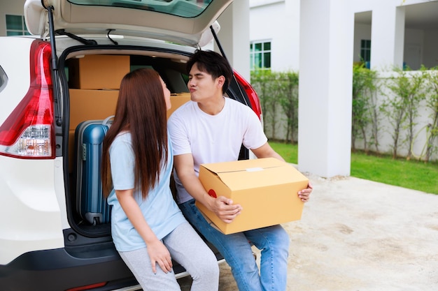 Feliz casal aisan ajuda a mover caixas de papelão para a nova casa juntos Dia da mudança