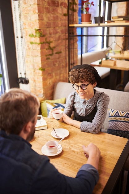 Feliz casal amoroso jovem sentado no café ou restaurante aconchegante, tomando chá e discutindo seus planos