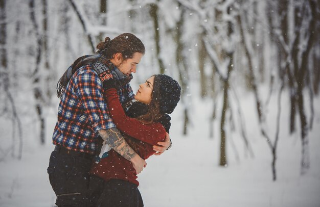 Foto feliz casal apaixonado andando no bosque nevado