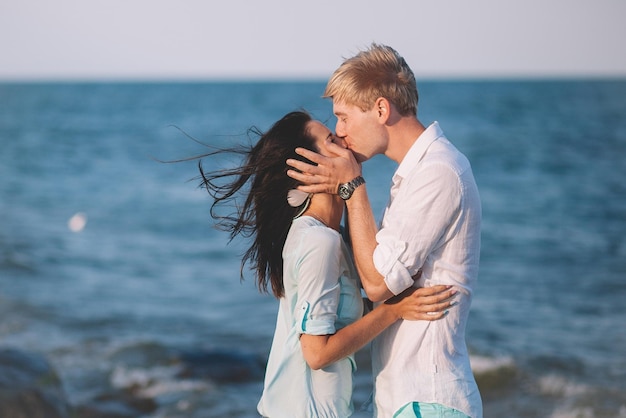 Feliz casal apaixonado contra o mar anda na praia contra o céu azul e se diverte no dia de verão União ama a família