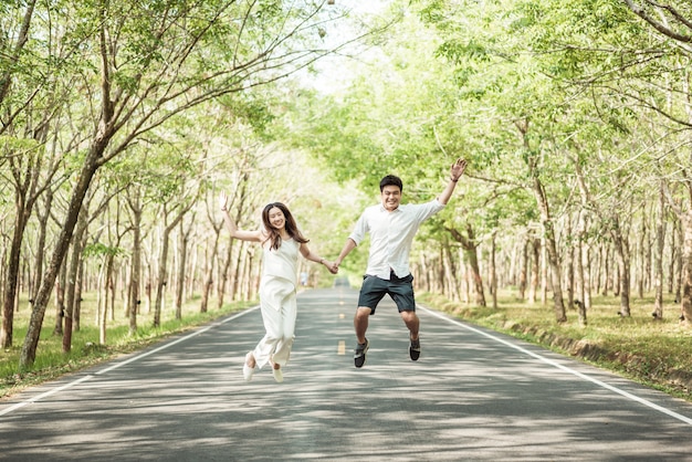 Feliz casal asiático apaixonado na estrada com arco de árvore