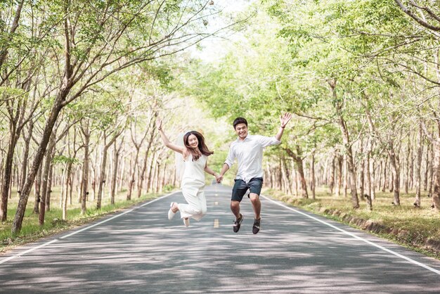 Feliz casal asiático apaixonado na estrada com um arco de árvore