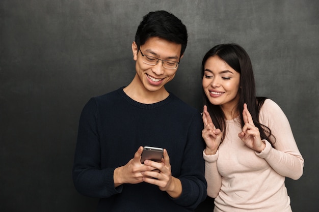 Feliz casal asiático juntos e usando smartphone