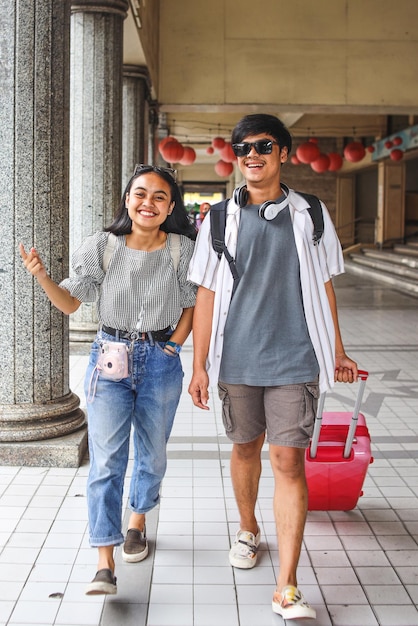 Feliz casal asiático turista passeando pela cidade com bagagem para viajar nos feriados