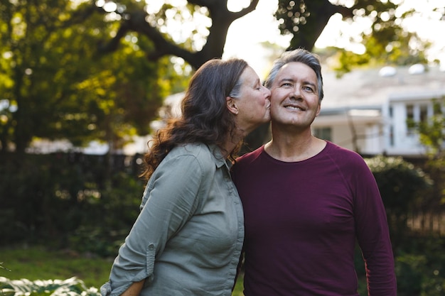 Feliz casal caucasiano sênior beijando e sorrindo no jardim. estilo de vida de aposentadoria, passando o tempo em casa.
