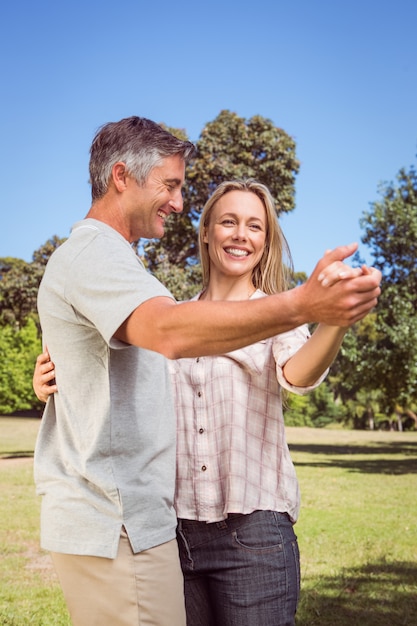 Feliz casal dançando no parque