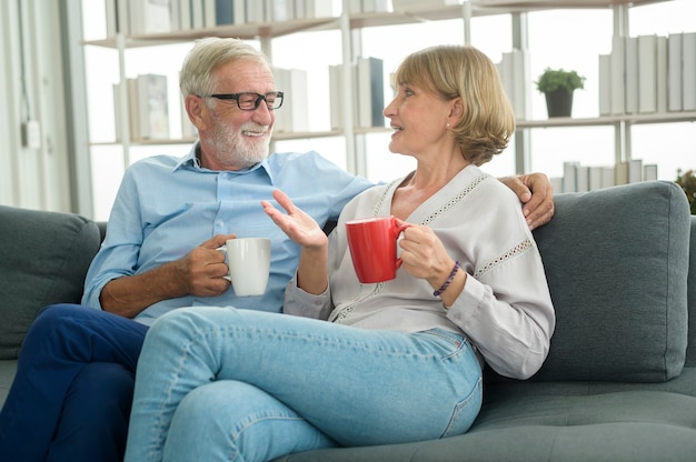 Feliz casal de idosos caucasianos está bebendo café em casa, o conceito de relaxamento e cuidados de saúde.