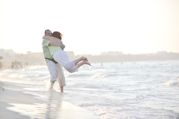 Feliz casal de idosos maduros tem tempo romântico na praia ao pôr do sol