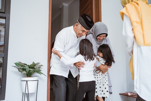 Feliz casal de idosos muçulmanos asiáticos conhecendo filhos e netos na porta da casa durante a celebração do eid mubarak