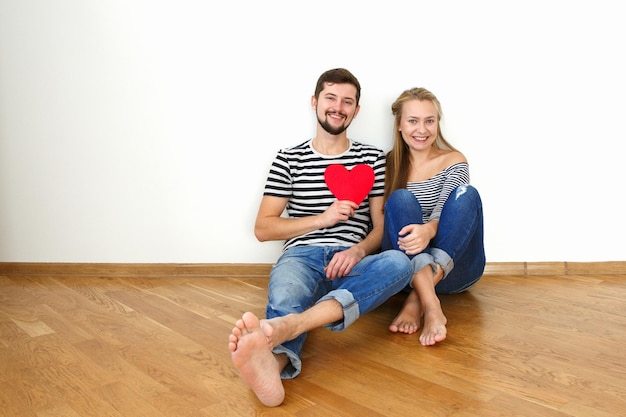 Feliz casal de namorados sentado em um piso de madeira Espaço de cópia de fundo branco