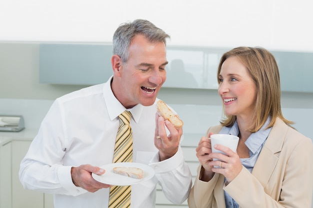 Feliz casal de negócios tomando café da manhã na cozinha