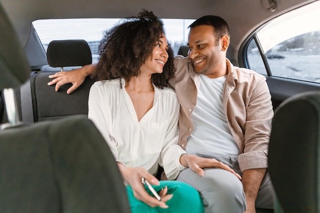 Foto feliz casal de passageiros árabes sentado no banco de trás do carro