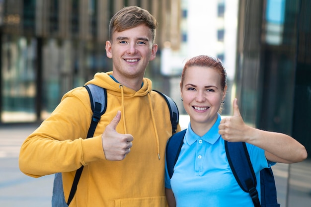 Feliz casal jovem europeu positivo, amigos, estudantes universitários ou universitários bem sucedidos com mochilas sorrindo juntos ao ar livre do campus.