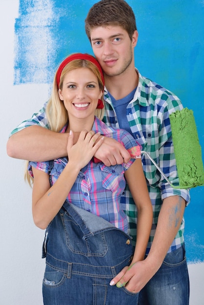 feliz casal jovem pinta na parede branca de cor verde e azul de sua nova casa