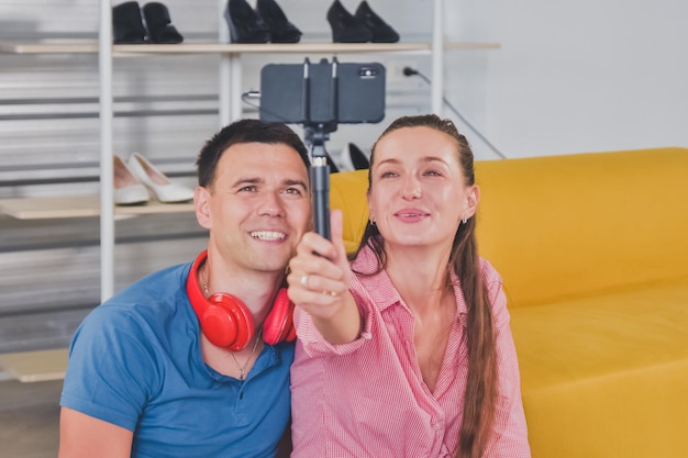Feliz casal jovem sorridente relaxando em um sofá em casa fazendo uma videochamada em família