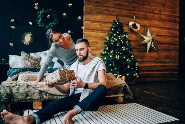 Feliz casal lindo com presentes de Natal no quarto aconchegante