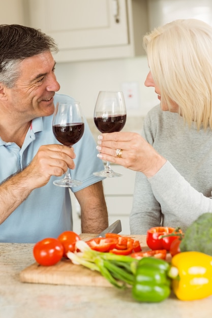 Feliz casal maduro com vinho tinto enquanto faz o jantar