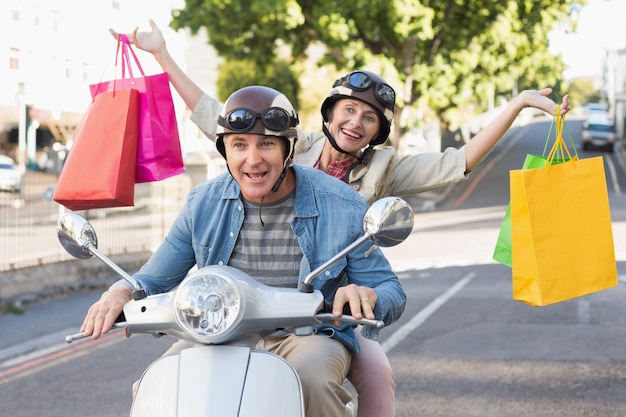 Foto feliz casal maduro montando uma scooter na cidade
