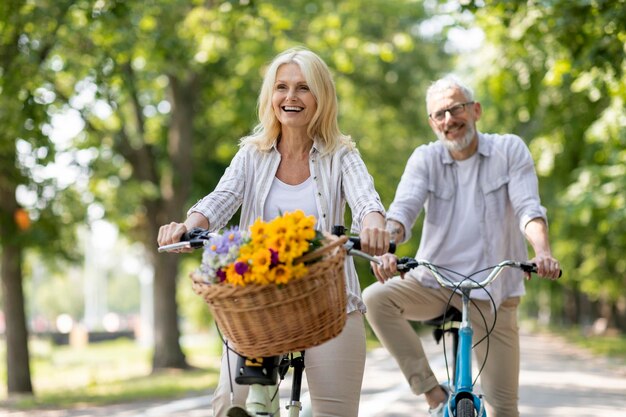 Feliz casal maturo alegre aproveitando o passeio de bicicleta no parque de verão