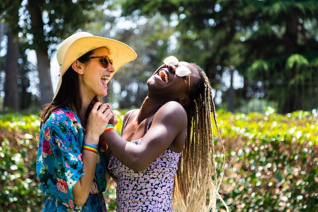 Feliz casal multirracial de mulheres gays riem juntos em um dia quente de verão no fundo desfocado. Copie o espaço. Conceito LGBT. Conceito de amor. Conceito de verão.