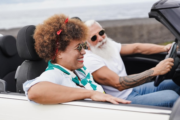 Feliz casal multitracial de idosos se divertindo dentro do carro conversível