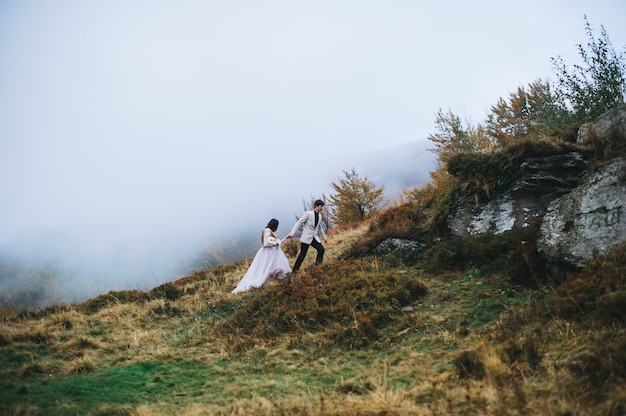 feliz casal recém-casado posando nas montanhas