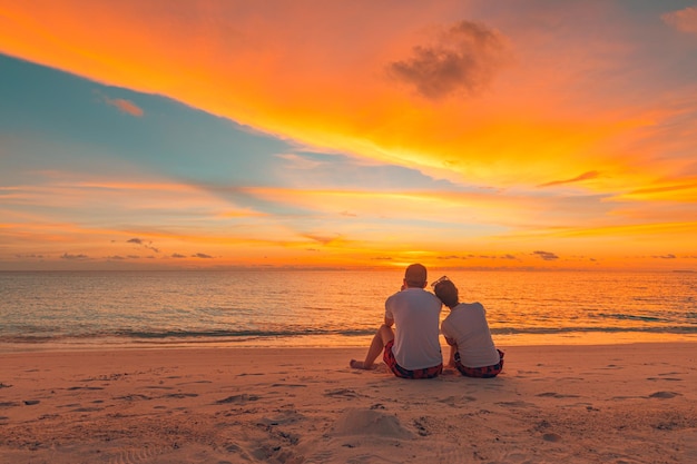 Feliz casal romântico assistindo o pôr do sol na paisagem de verão idílica de férias de praia tropical